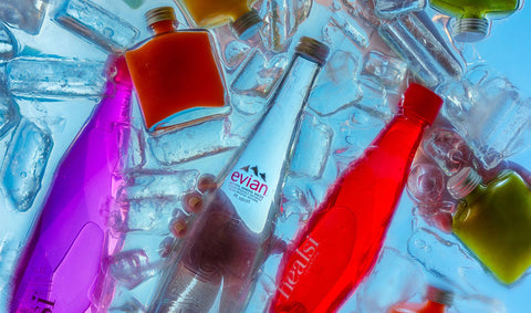 Colorful bottles of Evian, Healsi, and Joel’s Place powershots floating in iced water as a hand reaches in for a bottle