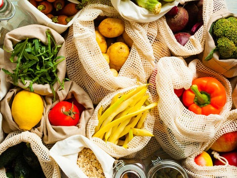 A wide shot of a variety of fresh produce, including fruits, vegetables, and other pantry staples stored in reusable textile bags and glass jars, highlighting seasonal ingredients from Joel’s Place.
