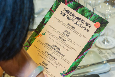 A close up of the Slow Food event menu at Joel's Place, held by a woman