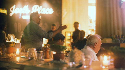 An image of an in-store news at Joel's Place showcases a lively dining experience during the “Boozy Barbecue Night” event, with several guests enjoying smoky grilled dishes and festive drinks at this social gathering.