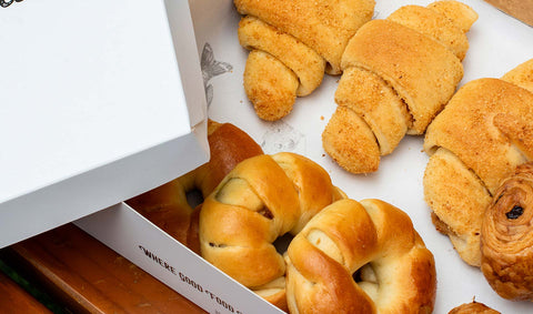 An photo of a box Joel's Place Pan de Coco and Spanish bread on a takeout box