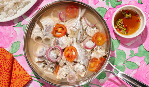 A pot of pinangat na sapsap next to dipping sauce and a plate of rice, on a pink floral tablecloth