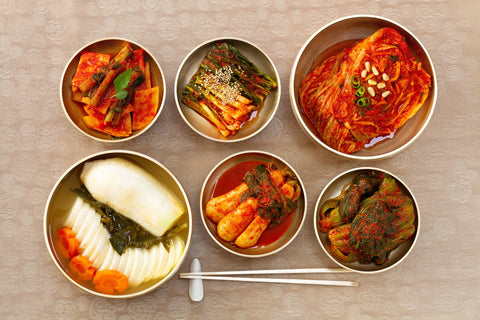 A flat lay photo of different kinds of kimchi, a Korean food staple, including cabbage kimchi and radish kimchi among others