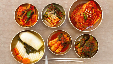 A flat lay photo of different kinds of kimchi, a Korean food staple, including cabbage kimchi and radish kimchi among others