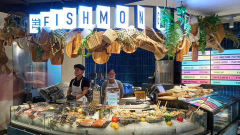Two attendants behind a display case featuring various seafood on ice at The Fishmonger section at Joel's Place Glorietta 4