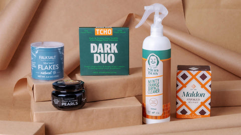 A photo of Joel's Place products in stacked in brown gift boxes and brown paper gift wrapping background