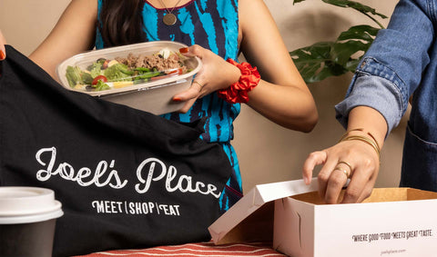 A lady getting ready-to-eat deli meals and picking up freshly baked cronadas via Joel's Place Click and Collect