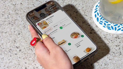 A close up shot of a person holding a mobile phone ordering from Joel's Place on GrabFood