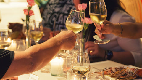 An image features an in-store news event at Joel's Place showcasing a social gathering during Lobster Medley filled with people toasting with wine glasses,  centered around lobster dishes and a fine dining setting.