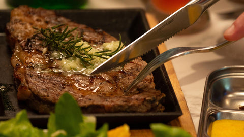 A close-up image of a pan-seared steak being sliced with a knife, showing how the consumer can choose a high-quality beef by understanding marbling and grading systems.