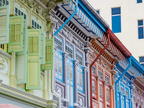 A close-up image of Singapore's colorful shophouses in light green, light blue, and red with intricate carvings. 