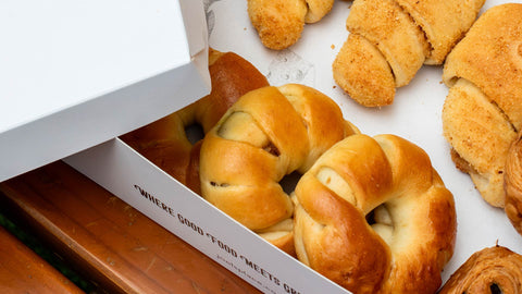 A photo of a box Joel's Place Pan de Coco and Spanish bread on a takeout box
