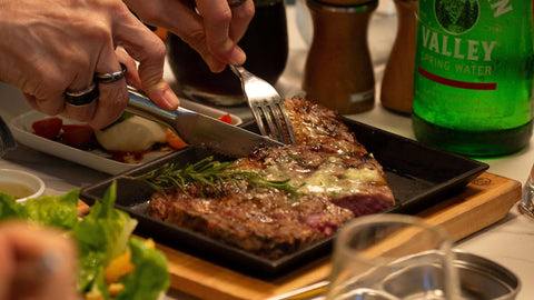 An image of a pan-seared steak being sliced with a knife and fork. 