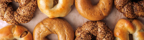 A close-up view of a flatlay image featuring freshly baked bagels, including traditional plain bagels and sesame-topped bagels.