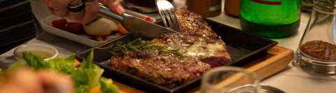 A close-up image of a pan-seared steak being sliced with a knife, showing how the consumer can choose a high-quality beef by understanding marbling and grading systems.