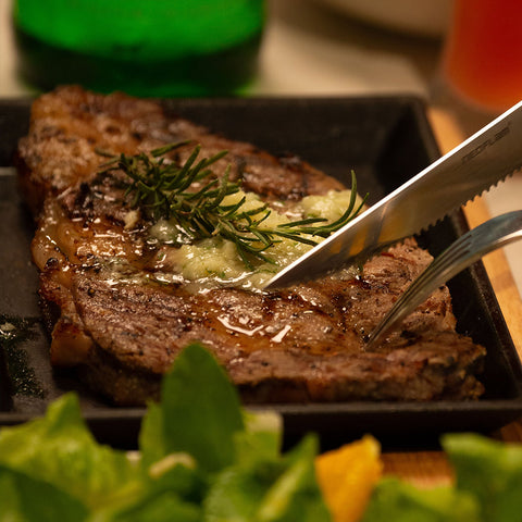 A close-up image of a pan-seared steak being sliced with a knife, showing how the consumer can choose a high-quality beef by understanding marbling and grading systems.
