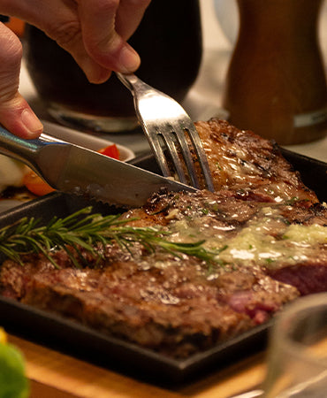 A close-up image of a pan-seared steak being sliced with a knife, showing how the consumer can choose a high-quality beef by understanding marbling and grading systems.