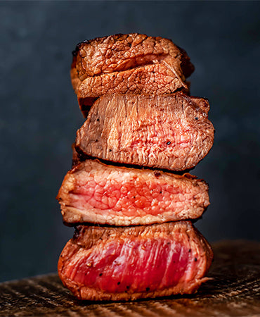 This image shows a vertical stack of steak, illustrating different internal cooking stages from top to bottom. 