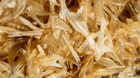 Close-up image of a pile of small dried fish with translucent golden colors.
